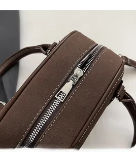 Detail view of brown leather Boston bag with smooth silver zipper and white contrast stitching
