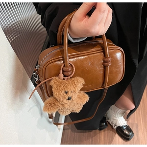 Dettaglio della borsa bowling vintage marrone lucida con ciondolo a forma di orsetto