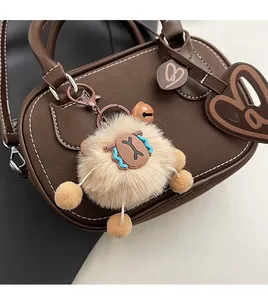 Detail of brown suede Boston bag with contrast stitching and cute sheep plush charm