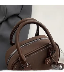 Detail of brown suede Boston bag showing contrast stitching and a heart-shaped B pendant
