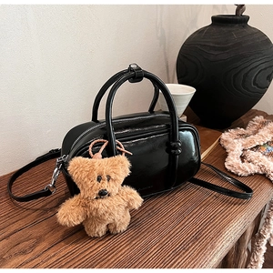 Dettaglio della borsa in pelle PU nera lucida con un grazioso ciondolo a forma di orso