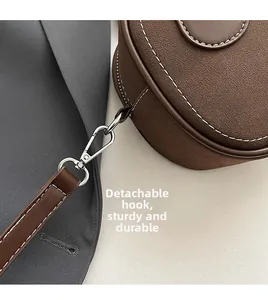 Detail of detachable metal hook and D-ring on retro brown bag with white stitching