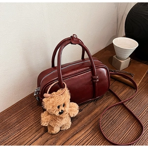 Dettaglio della borsa bowling in ecopelle bordeaux con finitura vintage e orsetto