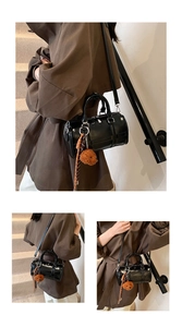 Detail view of black glossy Boston bag with bear charm and adjustable shoulder strap