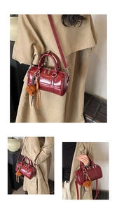 Detail view of burgundy PU bowling bag with detachable shoulder strap and teddy bear charm