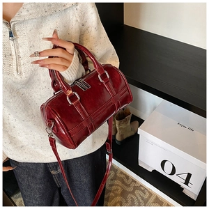 Detail view of burgundy leather boston bag with silver hardware and glossy finish