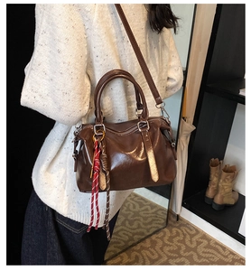 Detailweergave van donkerbruine glanzende Boston tas met verstelbare riem en hanger