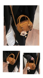 Detail of a brown Boston handbag featuring a plush sheep charm and heart pendant