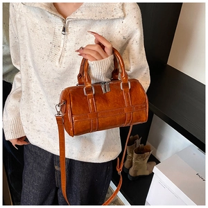Detail of retro brown PU bowling bag showing cross straps and silver hardware