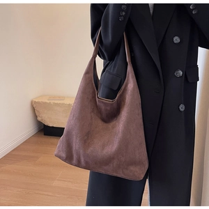Detail of a large brown suede tote bag featuring matte texture and a minimalist silhouette