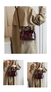 Gros plan du sac Boston rouge foncé au fini brillant avec doubles poignées et pendentif