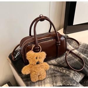 Dettaglio borsa bowling vintage marrone scuro con ciondolo a forma di orso e sciarpa