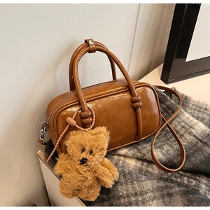 Dettaglio borsa bowling in pelle PU marrone con ciondolo a orsetto e logo inciso