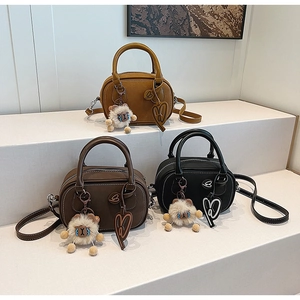 Detailed view of leather Boston bags in yellow, brown, and black with sheep pendants