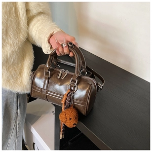 Close-up of dark brown glossy bowling bag with a cute puppy plush charm on table
