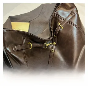 Detailed view of dark brown leather backpack with gold metal hardware and side drawstring