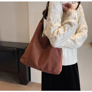 Detailed view of large brown suede tote bag worn over a soft knit sweater for autumn