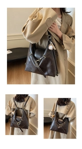 Detalle del bolso tote en cuero sintético marrón con correas ajustables y adorno de béisbol