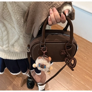 Detail of dark brown leather Boston bag with contrast stitching and cute bear charm