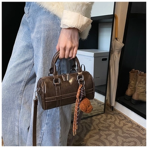 Detail view of coffee PU leather bowling bag with cute plush bear charm and twin handles