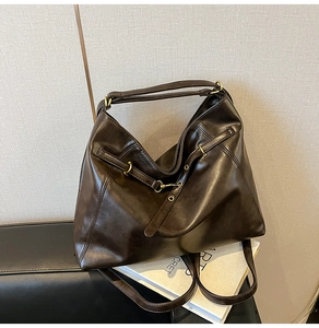 Detailed close-up of dark brown PU leather tote bag with glossy finish and metal buckles