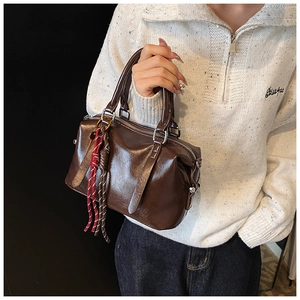 Détail du sac Boston en cuir ciré marron foncé avec un pendentif en corde tressée tricolore