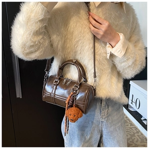 Detail of deep brown PU leather boston bag with a cute curly dog plush pendant