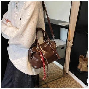 Détail du sac Boston en cuir ciré marron brillant avec bandoulière tressée chic