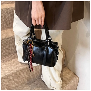 Détail d'un sac Boston noir en cuir ciré avec un pendentif clé dorée élégant