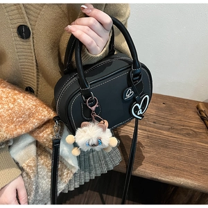 Detail of black Boston bag with white contrast stitching and cute plush charm detail