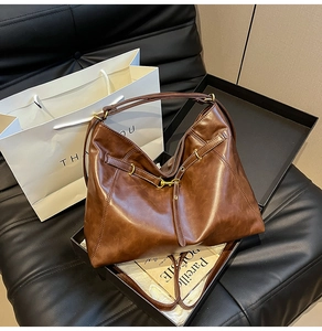 Detail of dark brown vintage faux leather tote bag with metal buckles and straps