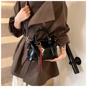 Détail d'un sac Boston en cuir ciré noir brillant avec un pendentif rayé décoratif