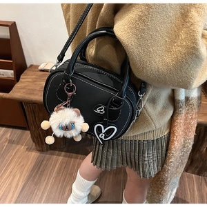 Detail of black leather Boston bag with white stitching and cute sheep charm on model
