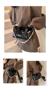Close-up of black glossy patent leather handbag featuring a silver hollow chain detail