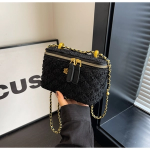 Close-up of black tweed crossbody bag with golden chain and floral zipper detail
