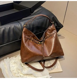 Detail of brown leather hobo bag with gold metal buckle and vintage minimalist design