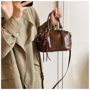 Détail du sac Boston en cuir ciré marron avec corde tissée décorative et poignées rigides