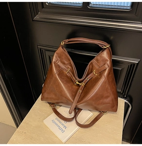 Close-up of dark brown vintage leather tote with metal buckle and matte texture