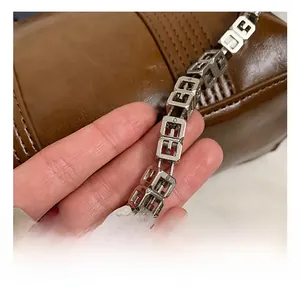 Macro shot of silver metal square chain with logo detail on a brown leather handbag