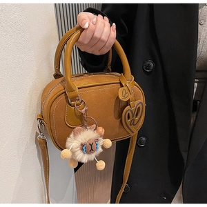 Detail view of caramel Boston bag with plush sheep charm and leather heart pendants