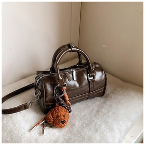 Close-up of brown PU leather bowling bag with dog charm and metal zipper details