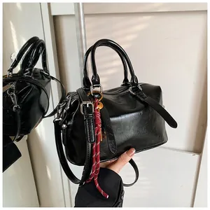 Détail du sac Boston noir avec pendentif en corde rouge et ferrures en argent poli