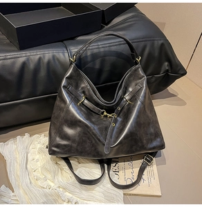 Close-up of black hobo tote bag with vintage oil-wax leather texture and brass hardware