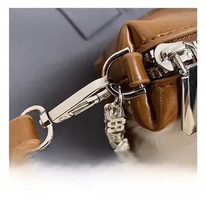 Close-up of premium silver metal hook and zipper on a brown leather shoulder bag