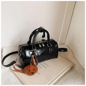 Detail of black bowling bag with dual zippers and a cute teddy charm on a book