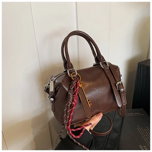 Détail du sac Boston en cuir ciré marron foncé avec clé dorée et breloque tissée chic