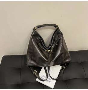 Detail of vintage grey tote bag with wrinkled leather texture and gold hardware hooks
