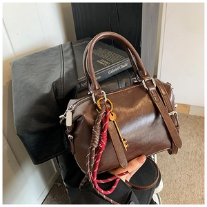 Détail du sac Boston en cuir ciré marron foncé avec pendentif clé en métal argenté brillant
