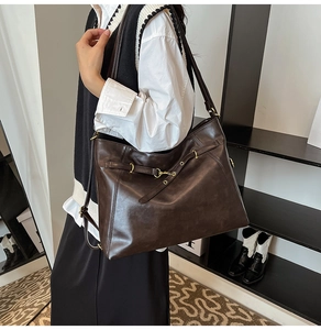 Detailed view of the dark brown leather tote bag with gold ring buckle and fine texture