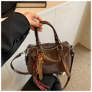 Détail du sac Boston en cuir huilé avec pendentif clé vintage et pompon élégant